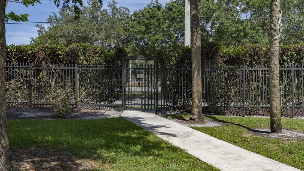 a sidewalk in front of a fence with a gate