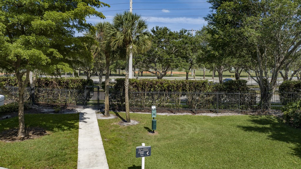 a park with trees and a fence and a sidewalk