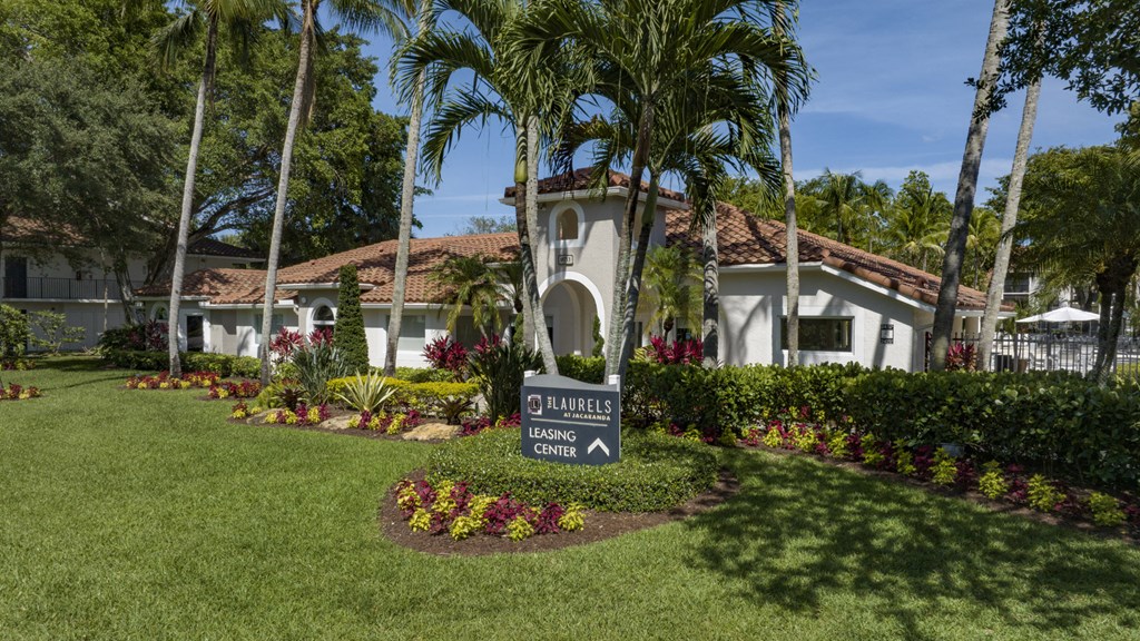 a sign in front of a house with palm trees