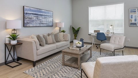 A living room with a beige sofa, a coffee table, and a painting on the wall.