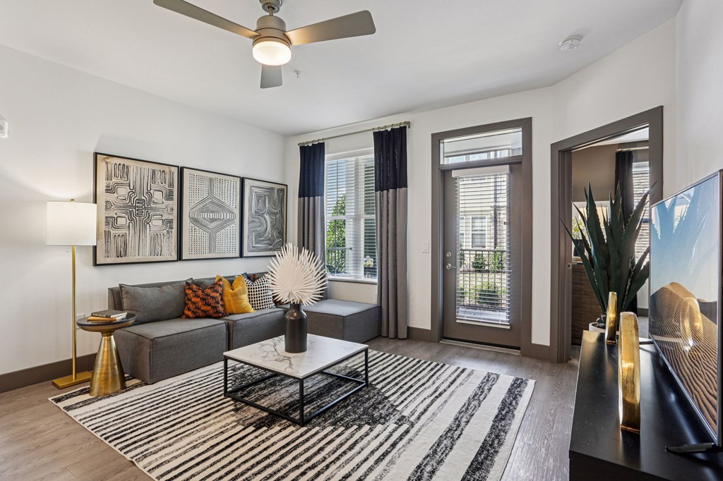 A living room with a grey couch, a coffee table, and a ceiling fan.