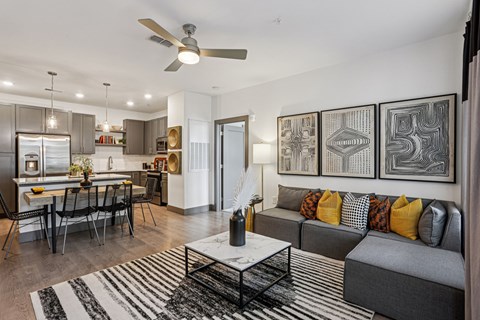 A modern living room with a grey sofa and a black and white rug.