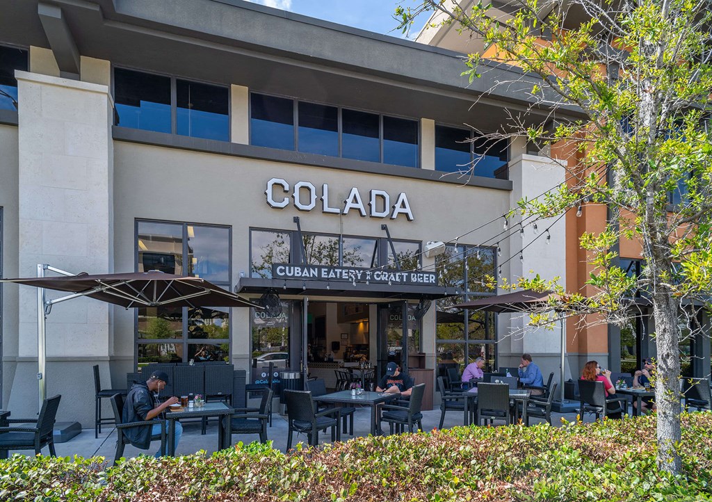people sitting at tables outside of a colada restaurant