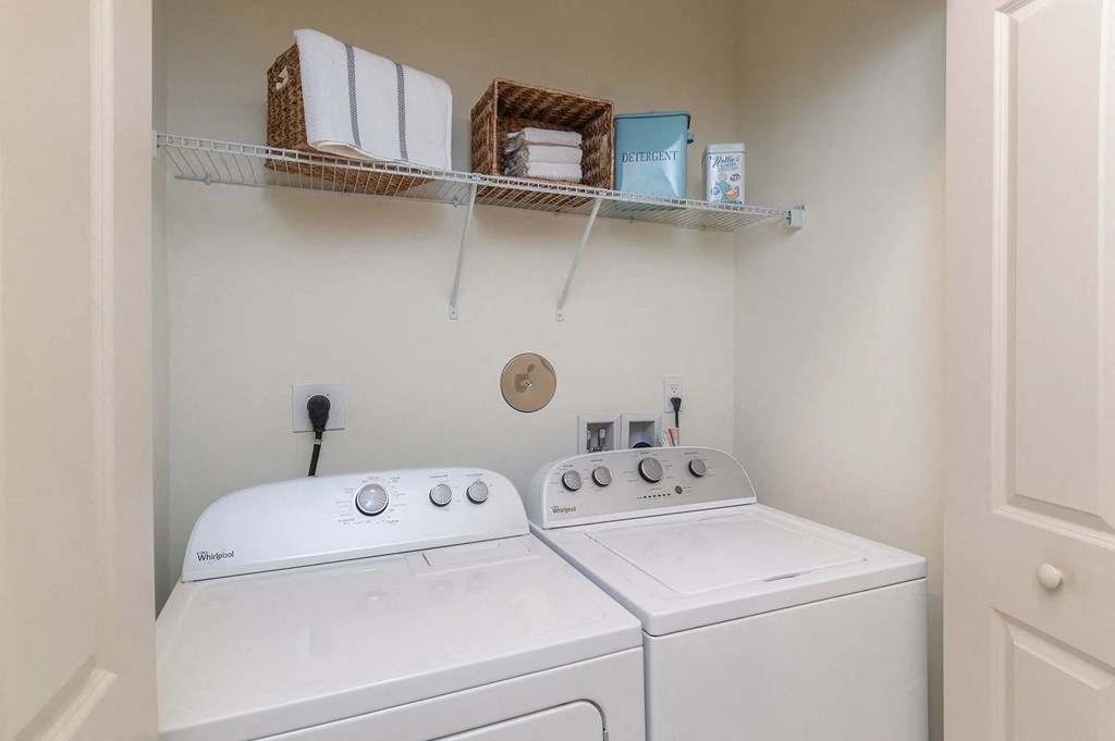 a washer and dryer in a white laundry room with shelves