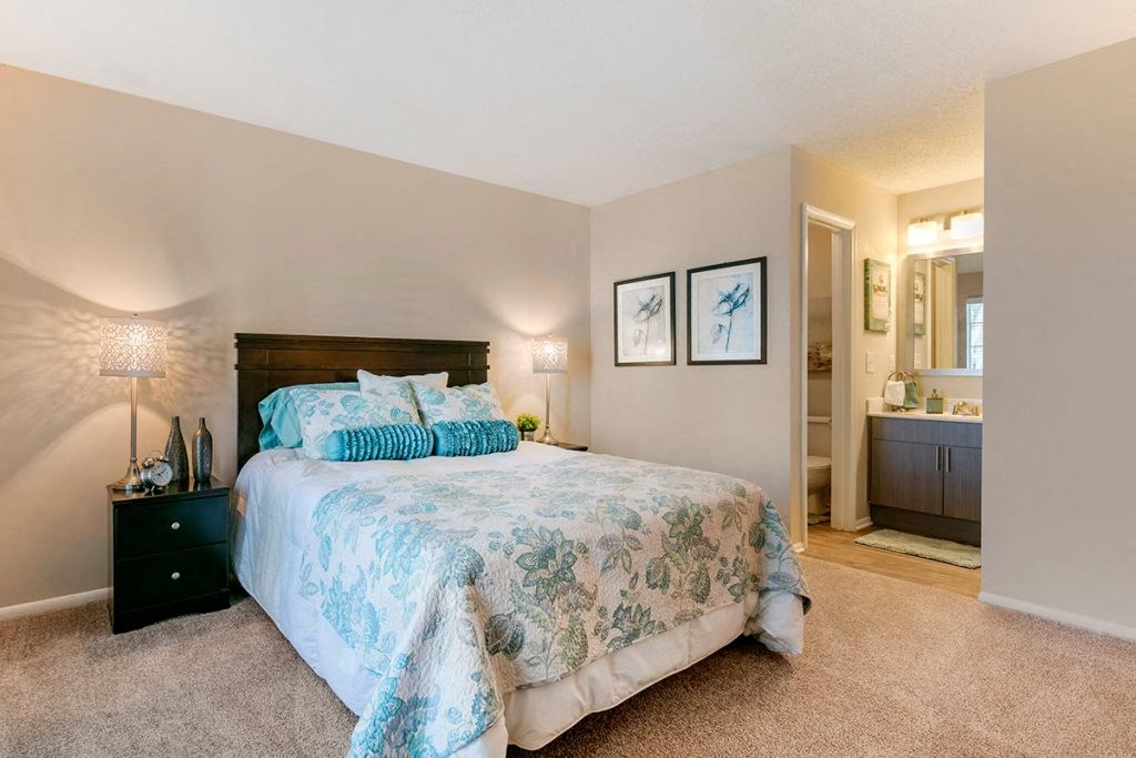 a bedroom with a bed and a bathroom in the background