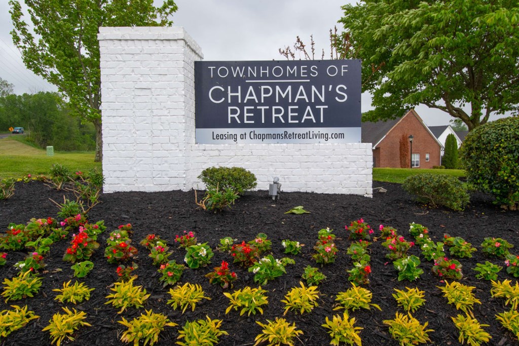 A sign for the Townhomes of Chapman's Retreat is surrounded by flowers.