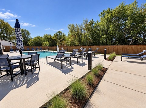 A poolside area with chairs and a table.