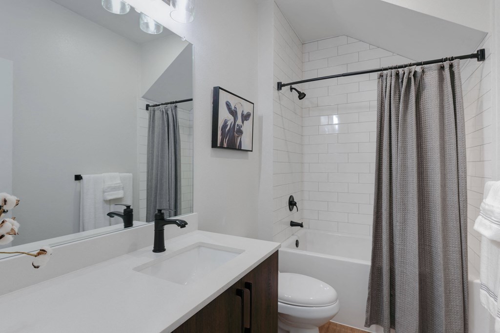 A bathroom with a white countertop and a white tiled wall.