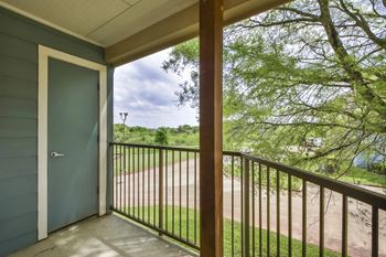 A view from a balcony looking out to a tree and a path.
