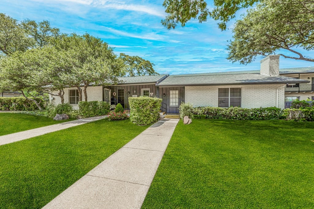 the front of a house with a lawn and sidewalk