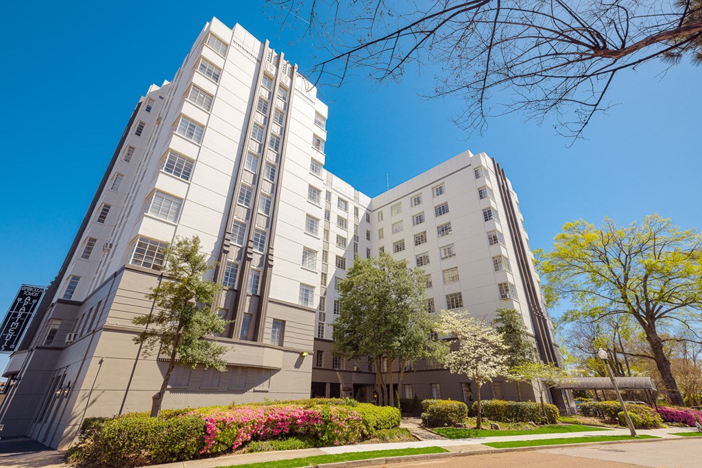 a white building with trees in the foreground and a blue sky in the background