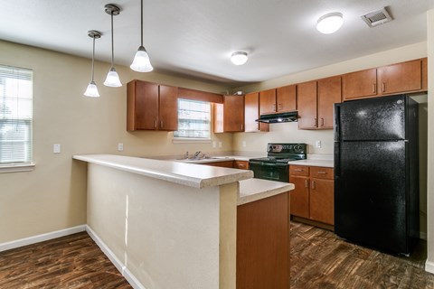A kitchen with a black refrigerator and wooden cabinets.