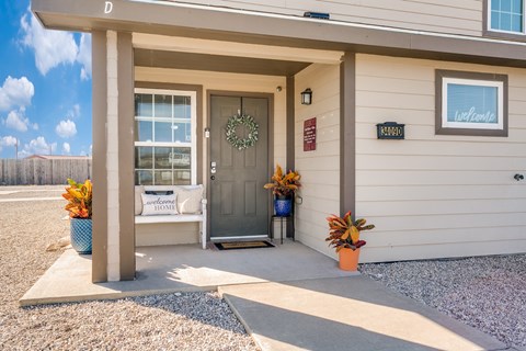 A house entrance with a wreath on the door and a sign that says "Welcome Home".