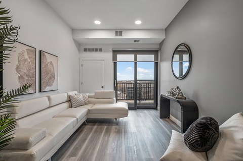 A modern living room with a white couch and a round mirror on the wall.