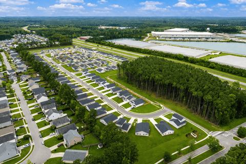 A bird's eye view of a residential area with houses and a large building in the distance.