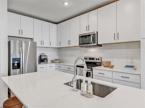 a white kitchen with a sink and a microwave