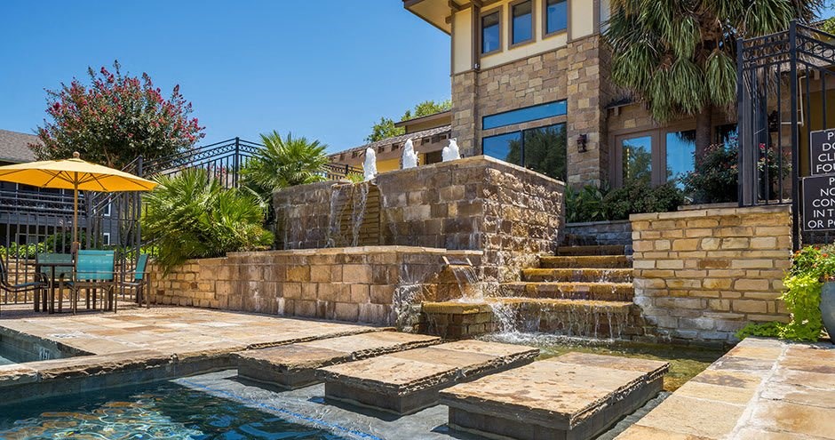 a swimming pool with a waterfall in front of a house