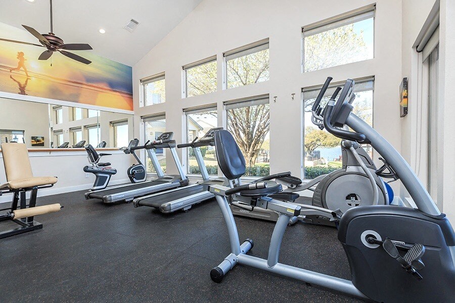 A gym with treadmills, exercise bikes, and a fan.