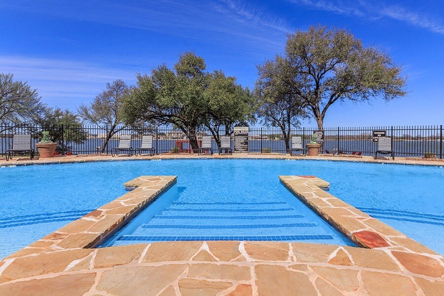 A swimming pool with a stone border and steps leading into the water.