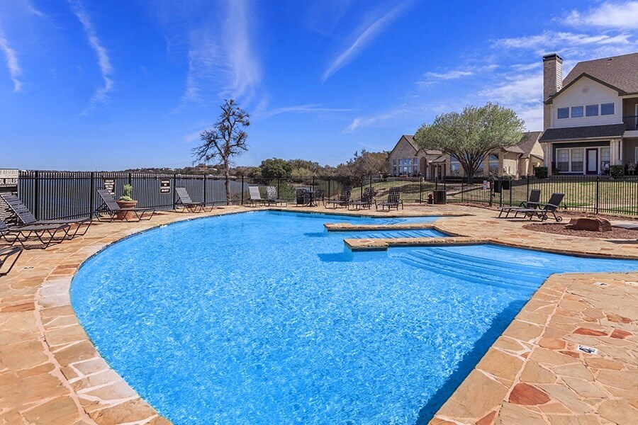 A large outdoor swimming pool surrounded by a stone border.