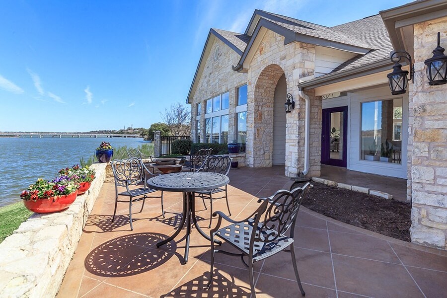 A patio with a table and chairs overlooking a body of water.