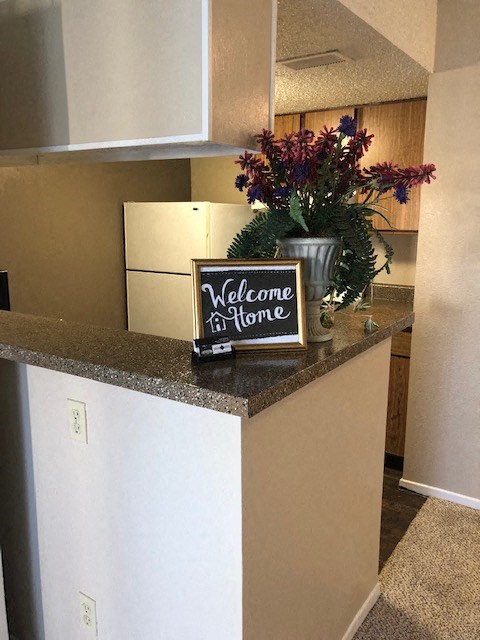 a kitchen counter with a sign and flowers on it
