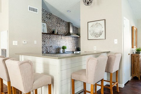 A kitchen with a bar area and chairs.