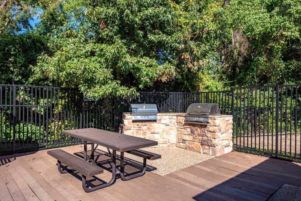 a patio with a picnic table and a barbecue grill