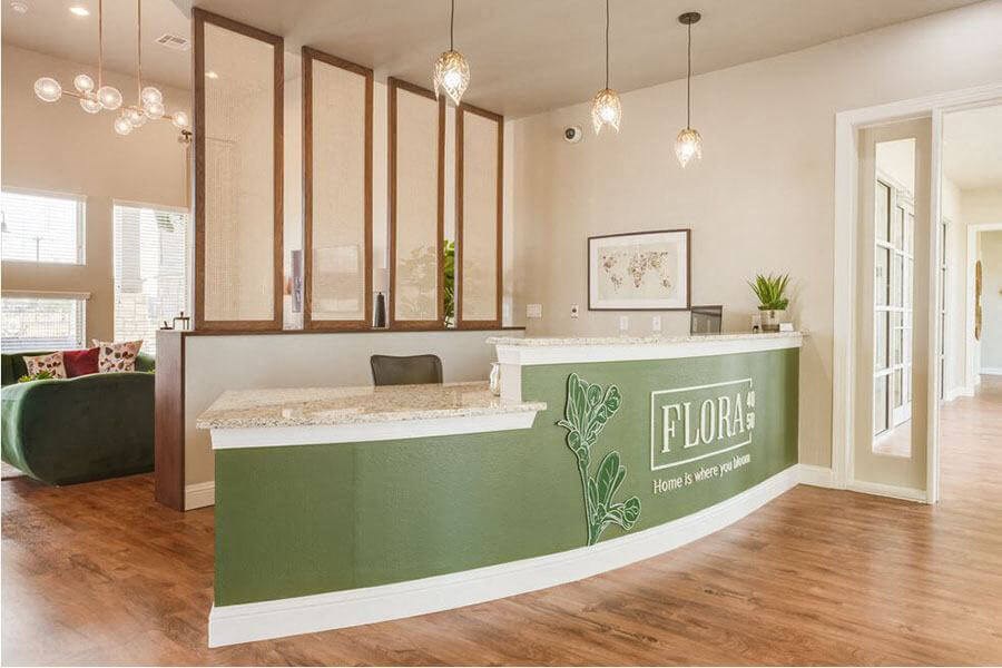 A reception area with a green counter and a sign that says "FLORA".