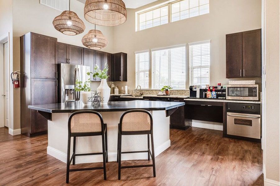 A kitchen with a black refrigerator and wooden floors.