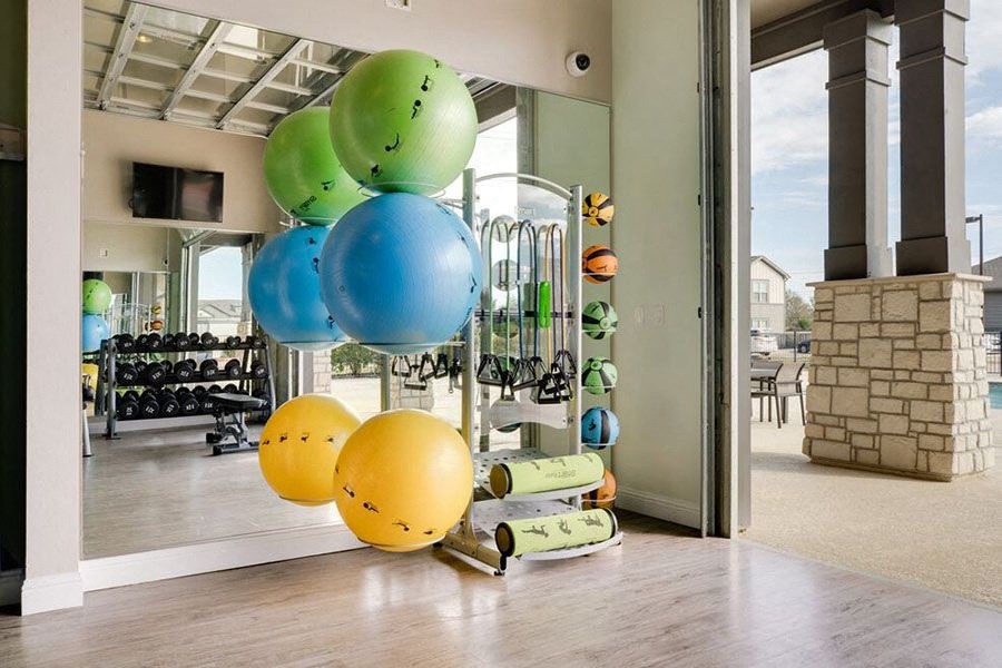 A room with a row of exercise balls of different sizes and colors.