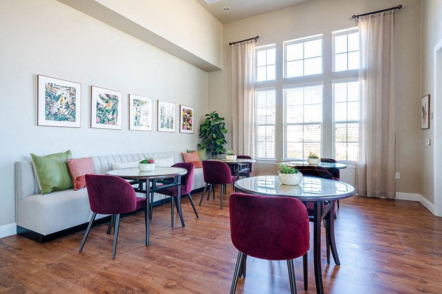A living room with a white couch, a dining table with chairs, and pictures on the wall.