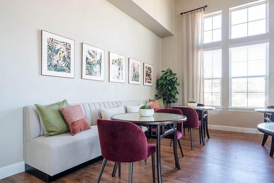 A living room with a white couch, a table with chairs, and pictures on the wall.