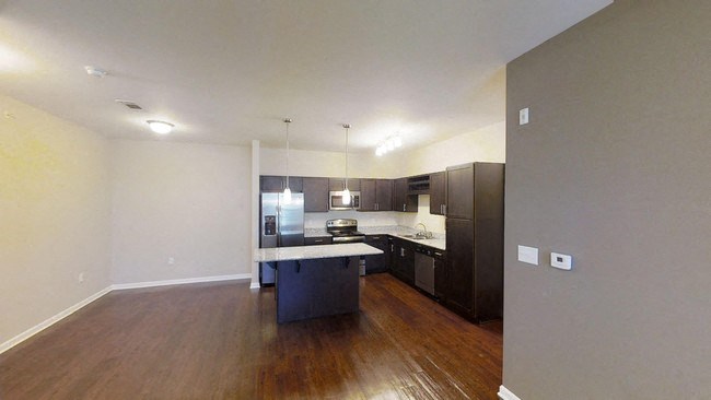 A kitchen with dark wood floors and white walls.