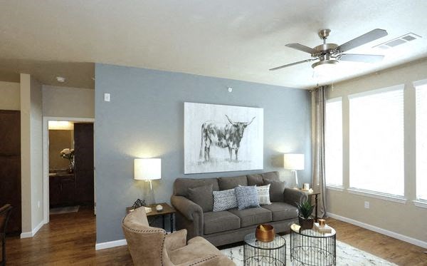 A living room with a grey couch and a painting of a deer on the wall.