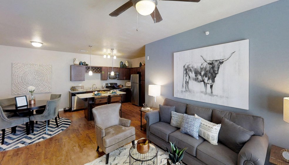 A living room with a grey couch and a painting of a bull on the wall.