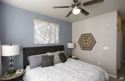 A bedroom with a bed, nightstand, and a ceiling fan.