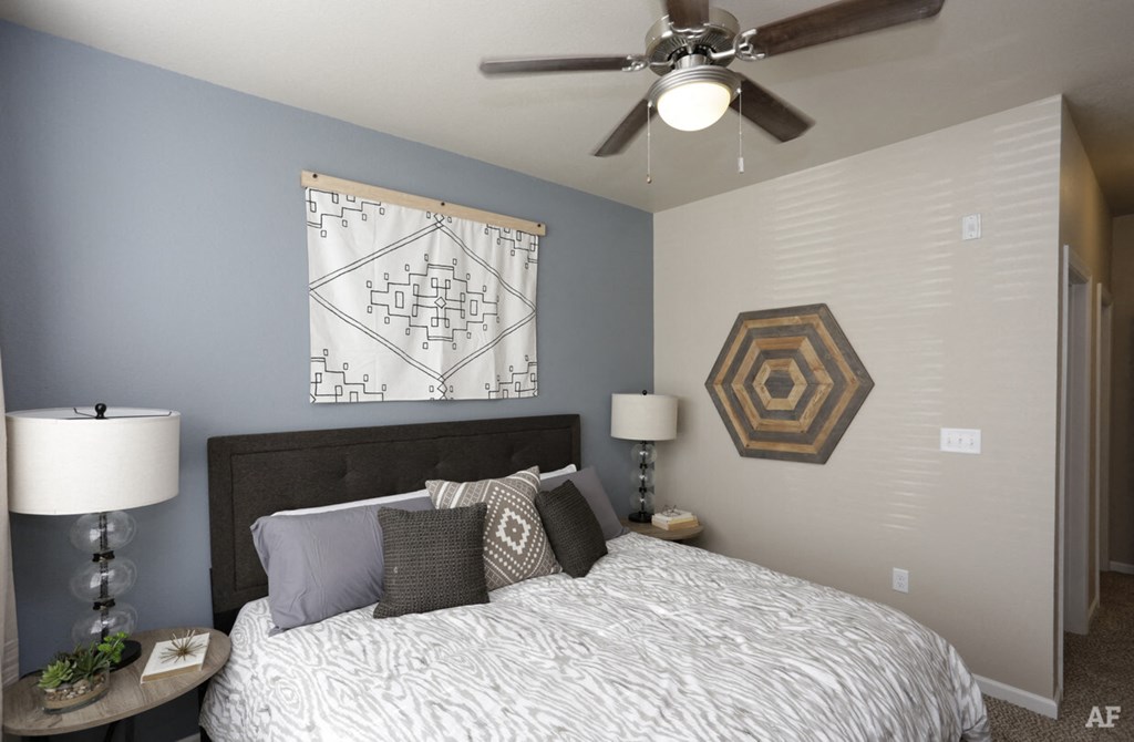 A bedroom with a bed, nightstand, and a ceiling fan.