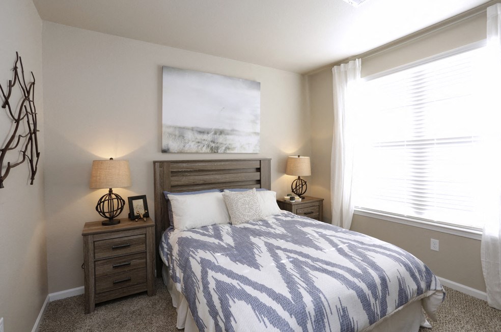 A bedroom with a bed, two lamps, and a painting on the wall.