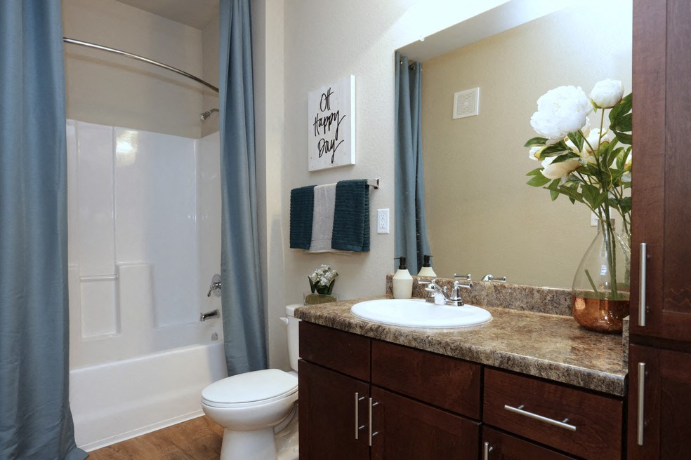 A bathroom with a toilet, sink, and a vase of flowers.
