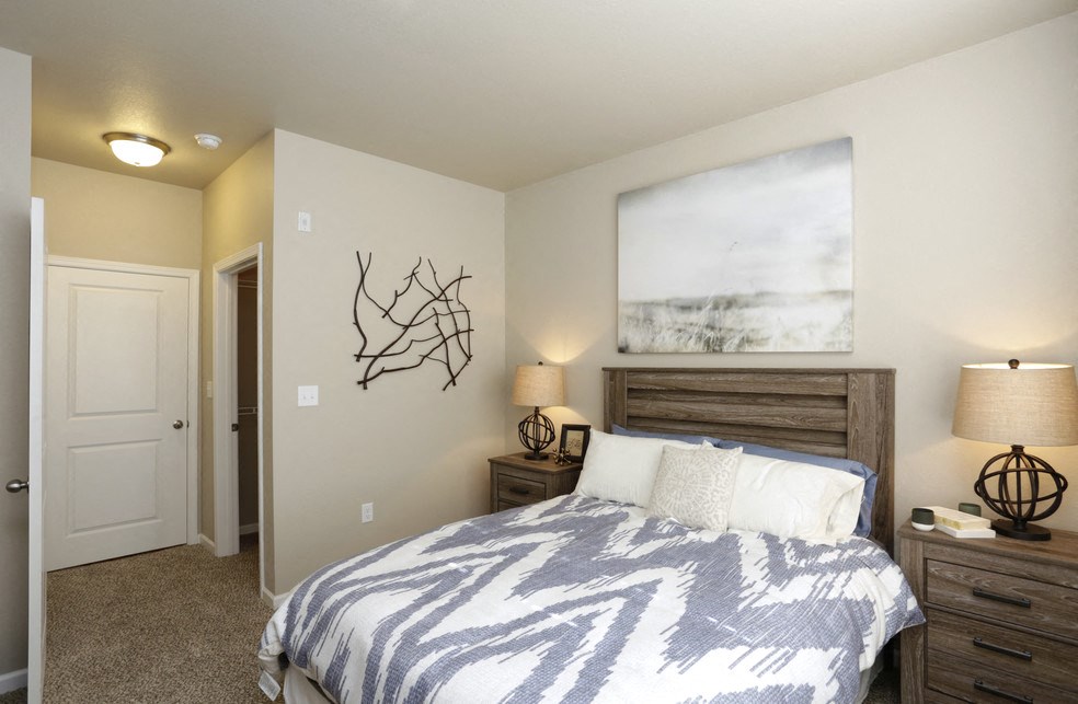 A bedroom with a bed, nightstands, and a wall art of a tree.