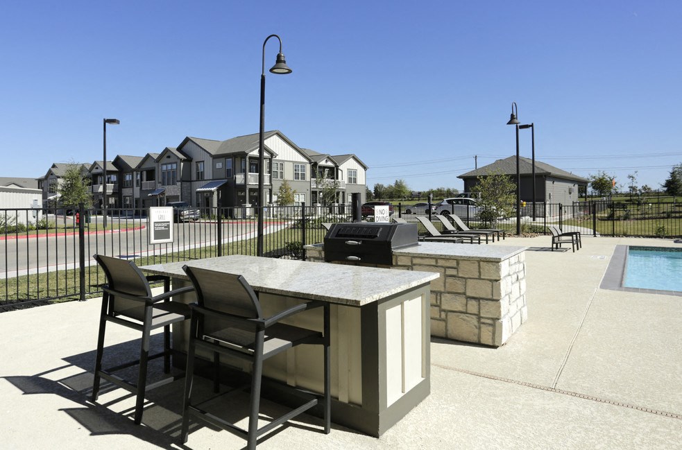 A patio with a table and chairs is in front of a house.