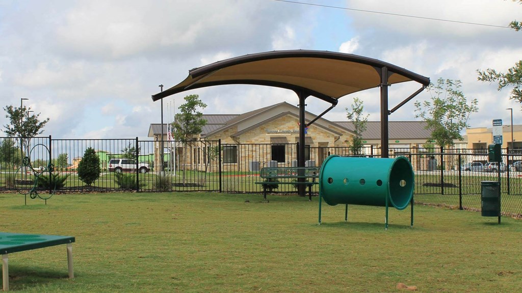 A green barrel under a canopy sits in a grassy field.