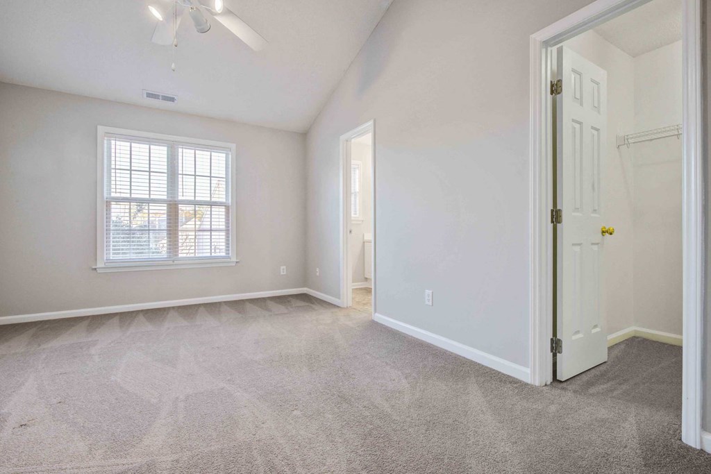 an empty living room with a white door and a window