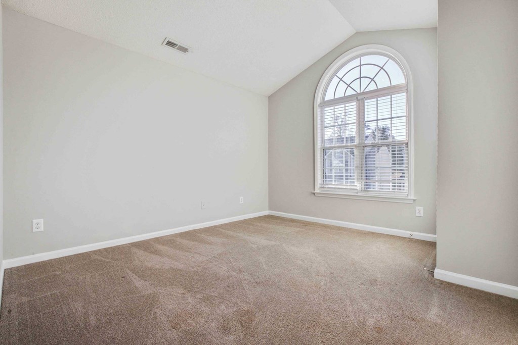 an empty living room with a large window and carpet