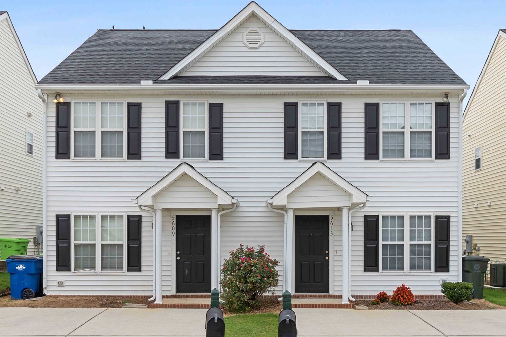 a white house with black shutters and a sidewalk