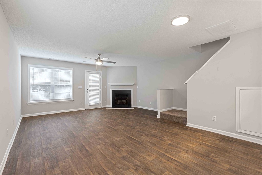 an empty living room with a ceiling fan and a fireplace