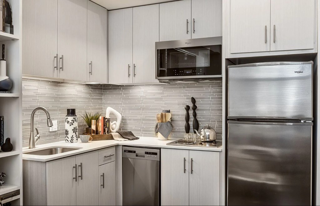 A modern kitchen with a stainless steel refrigerator and white cabinets.