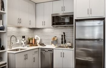 A modern kitchen with a stainless steel refrigerator and white cabinets.
