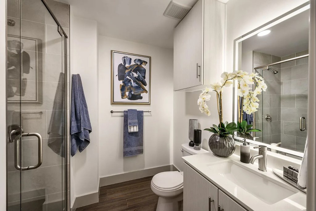 A bathroom with a toilet, sink, and a painting on the wall.